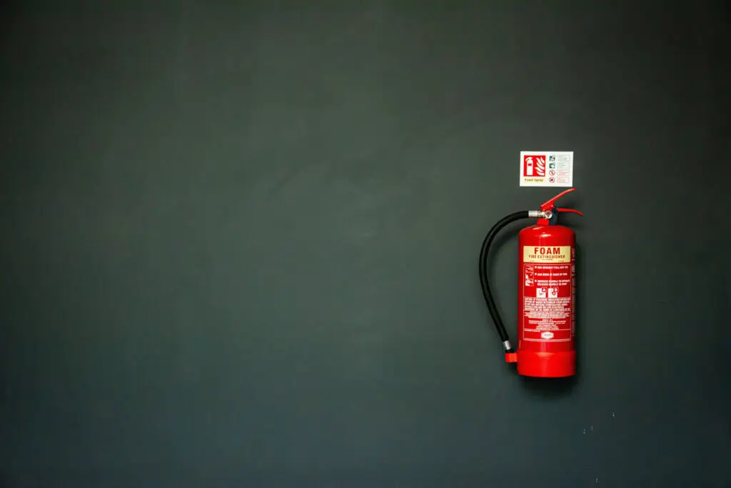 A red fire extinguisher on a green wall.