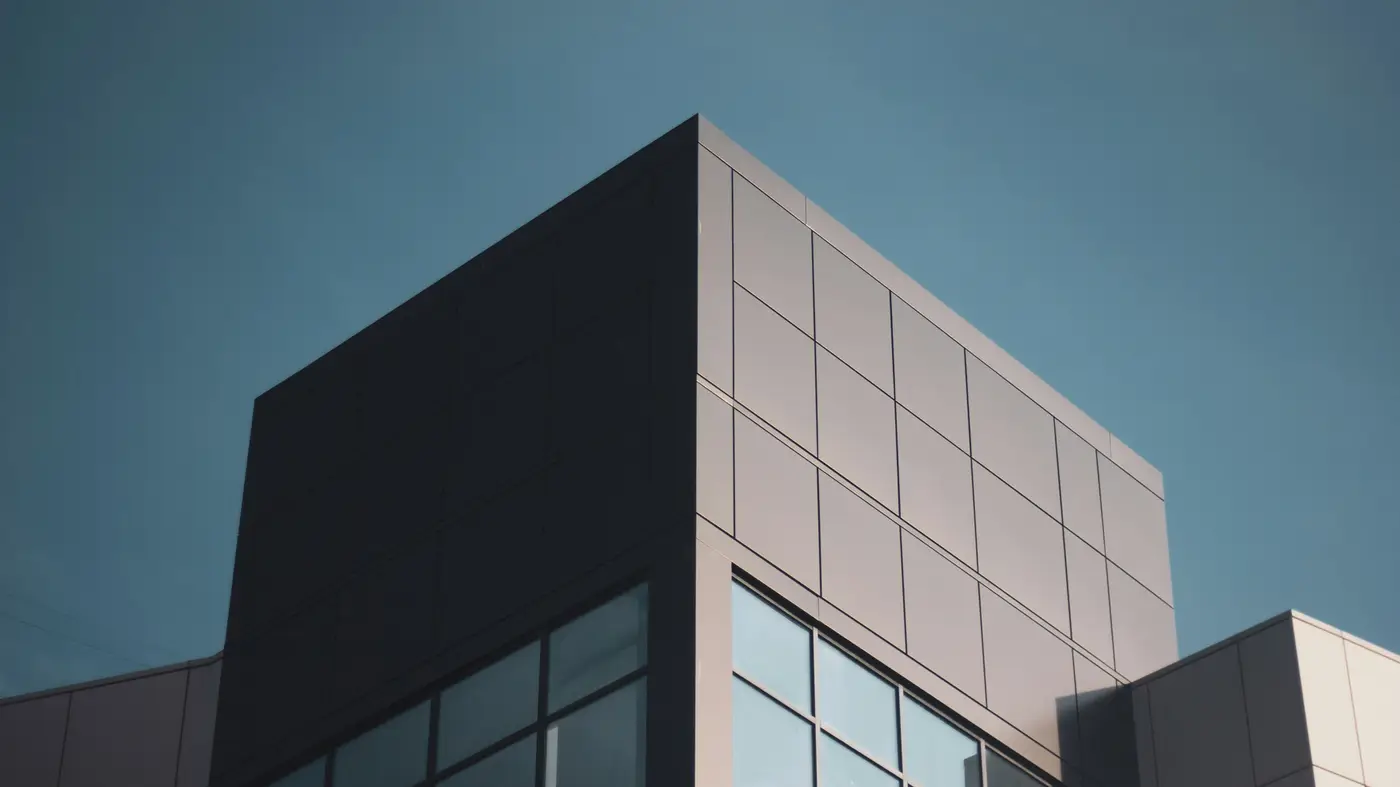 Looking up at the corner of an architectural building, clear blue sky in the background.